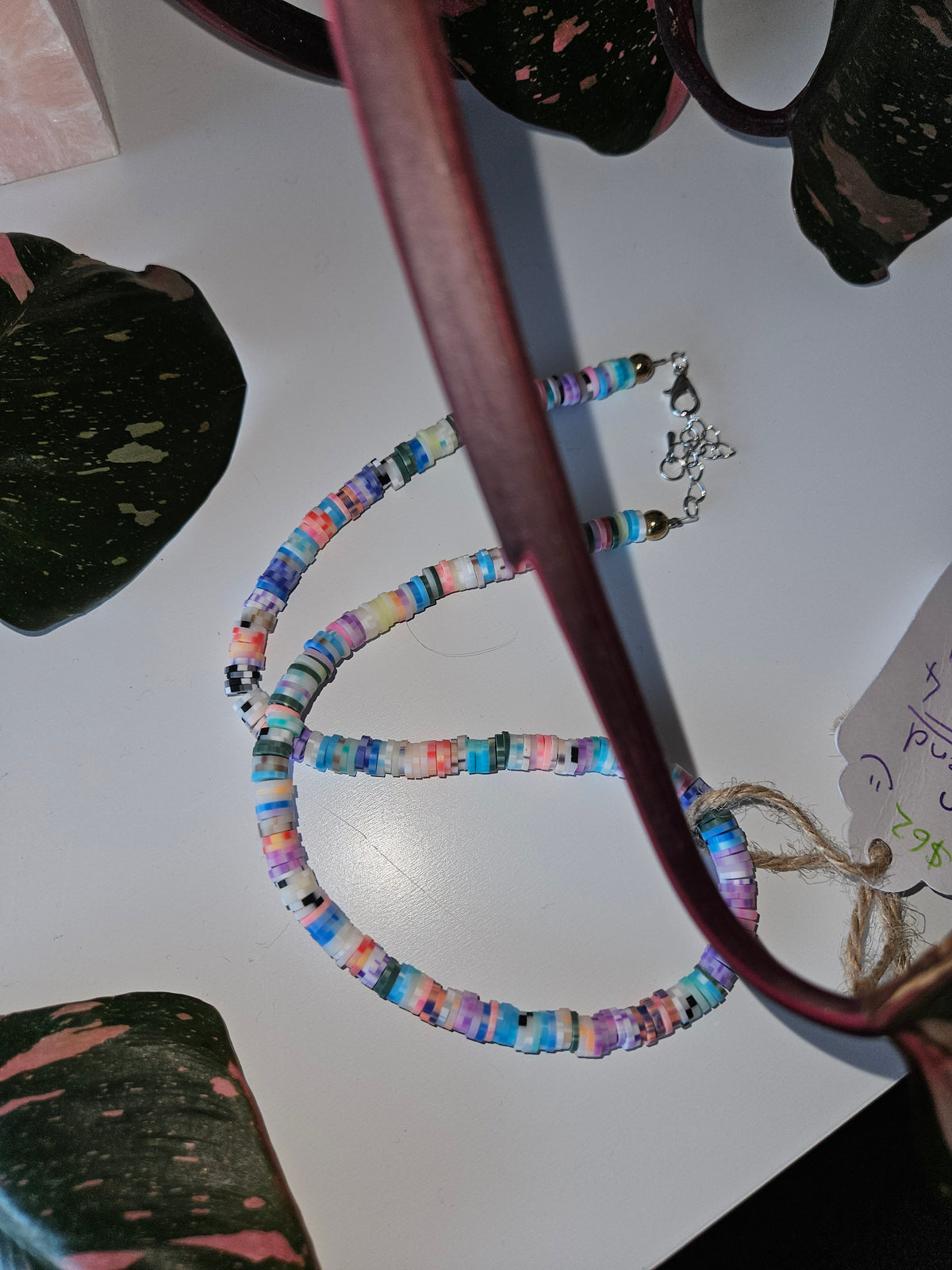 Multicolor clay disk bead necklace looped on display, both ends with lobster clasps.
