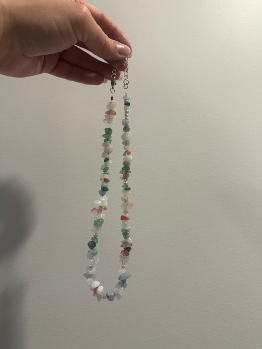 Multicolor crystal bead necklace on a hook, featuring white, green, red, and blue beads.