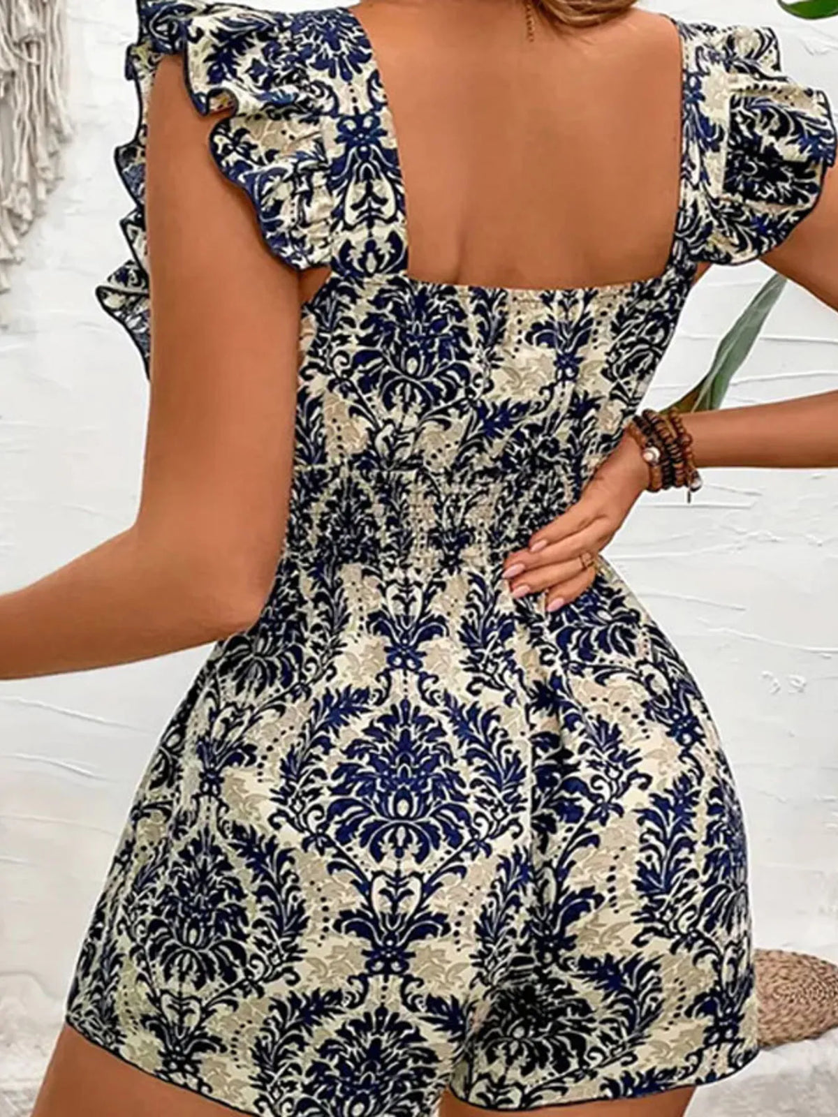 Navy-and-cream printed ruffle romper with square neckline and flared ruffle shoulders