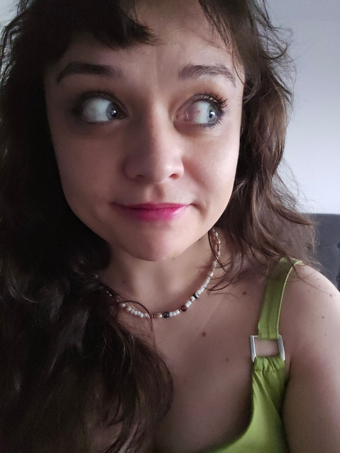 Close-up of a person with a green top and necklace, looking upwards.