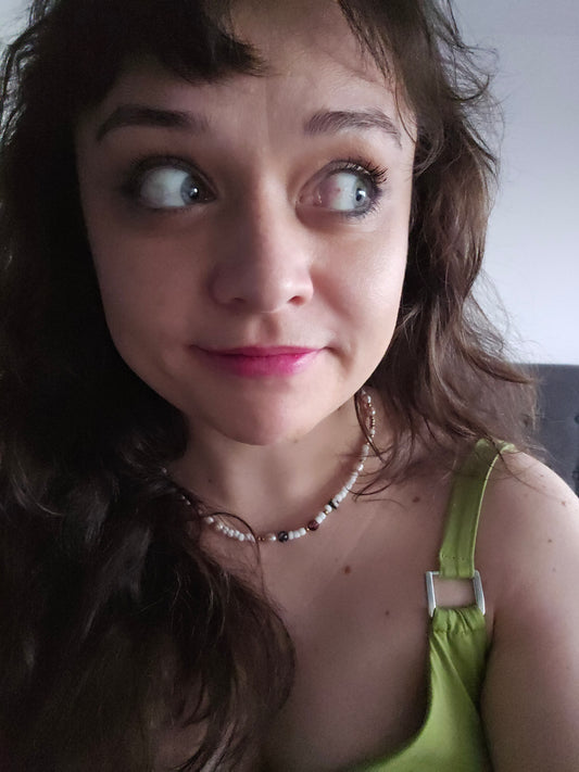 Close-up of a person with a green top and necklace, looking upwards.