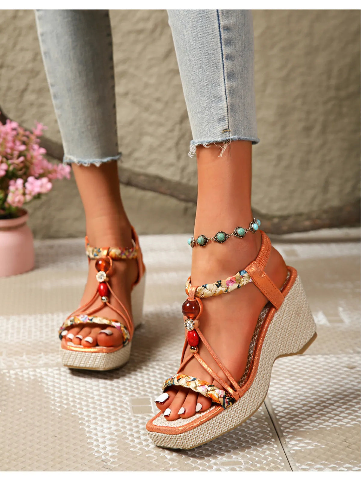 Wedge sandals with orange straps, beige textured wedge, and red bead details
