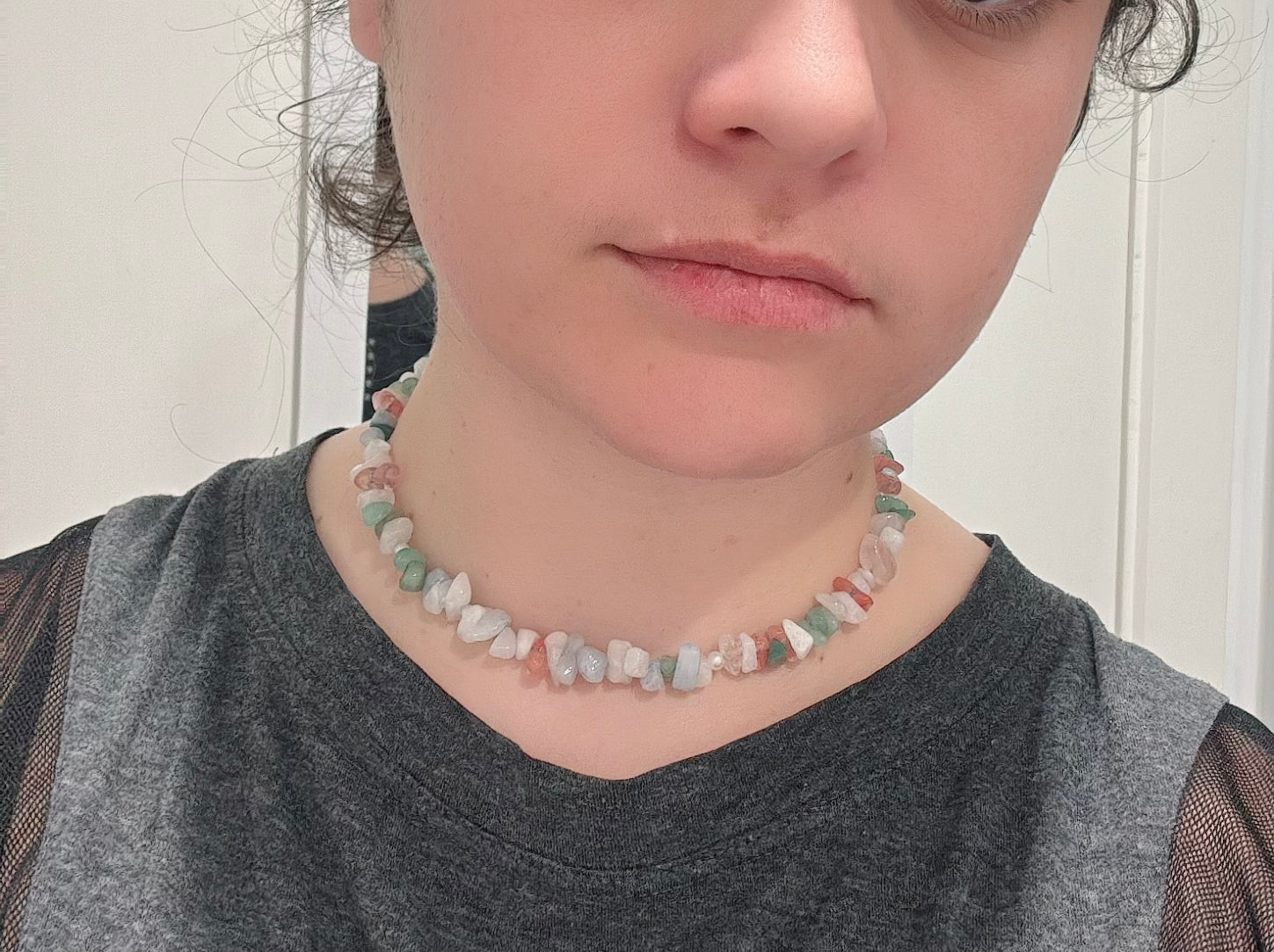 Pastel crystal bead necklace with mixed white, green, and red stones worn on the neck.