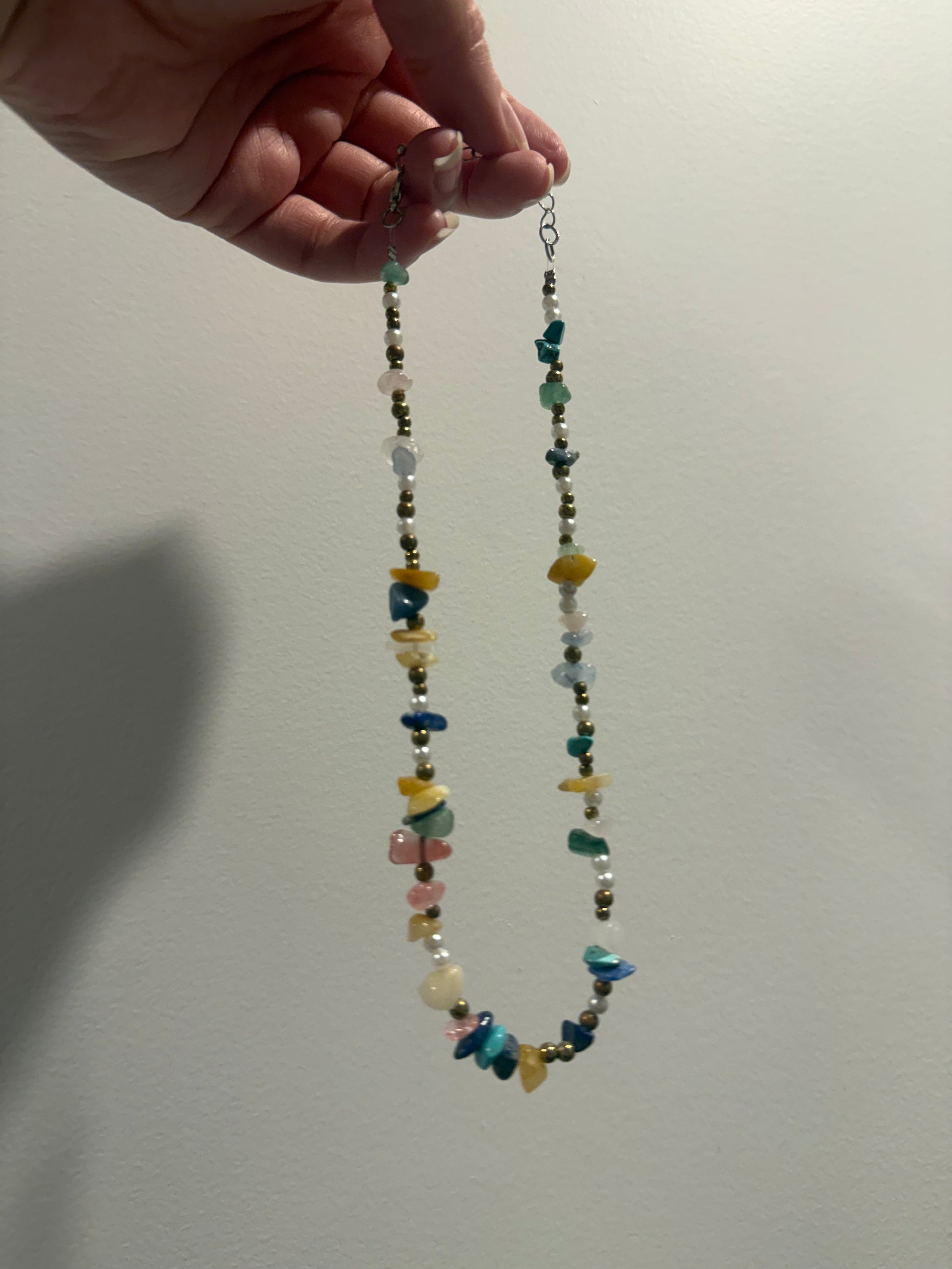 Long beaded crystal necklace with multicolor stones and a blue bead accent at the bottom.
