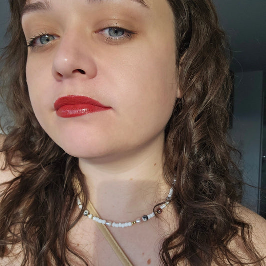 Close-up of a person with red lipstick and wavy hair.