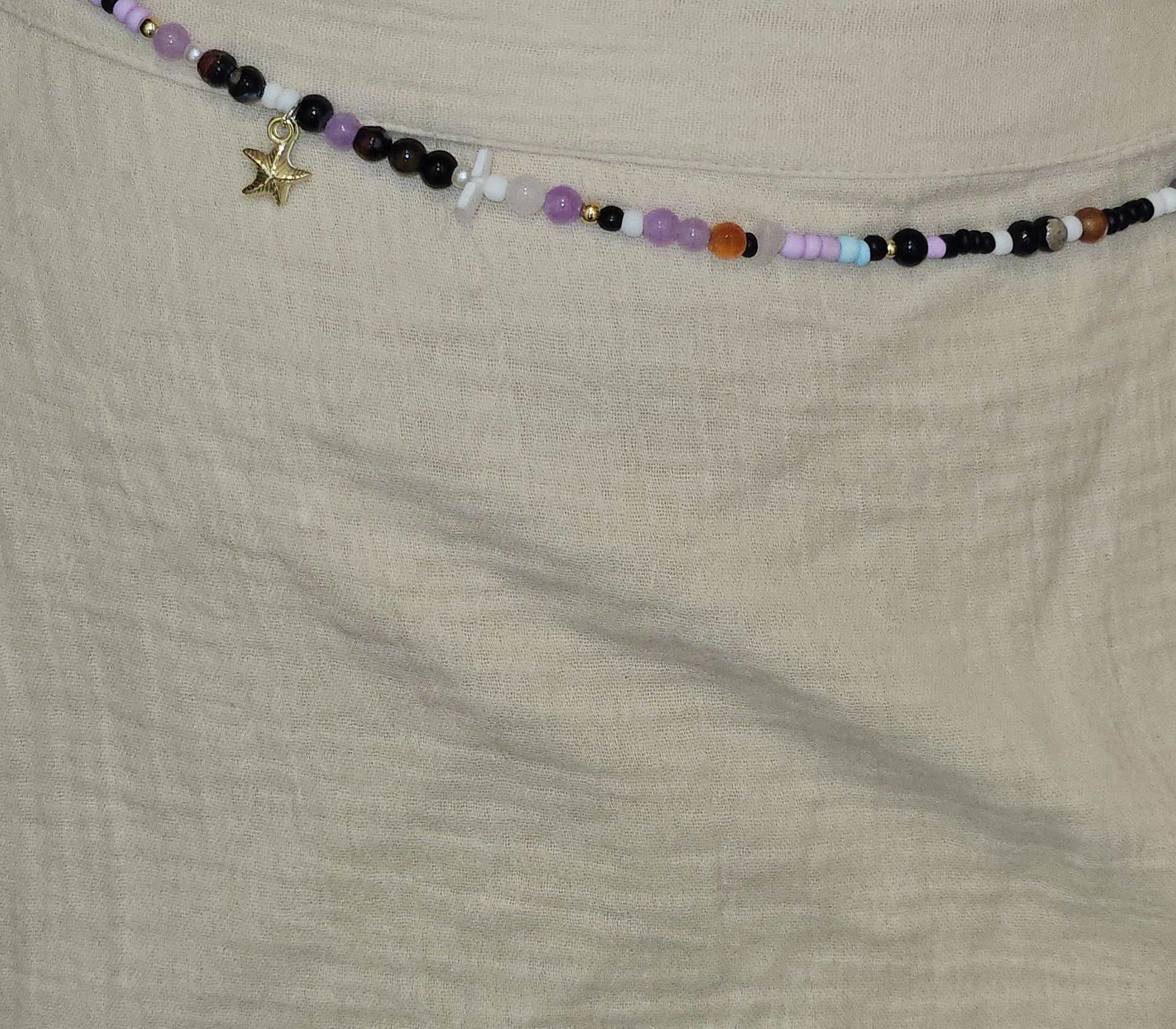 Beaded necklace with charms on a beige fabric background