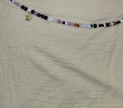 Beaded necklace with charms on a beige fabric background