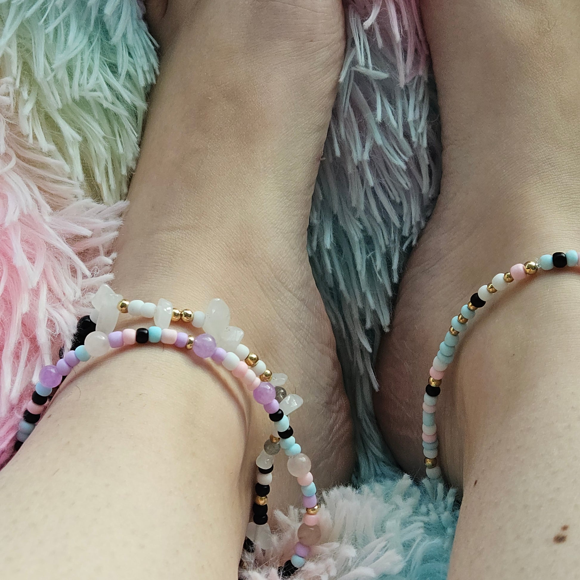 Close-up of a person's ankle with a beaded anklet on a textured surface.