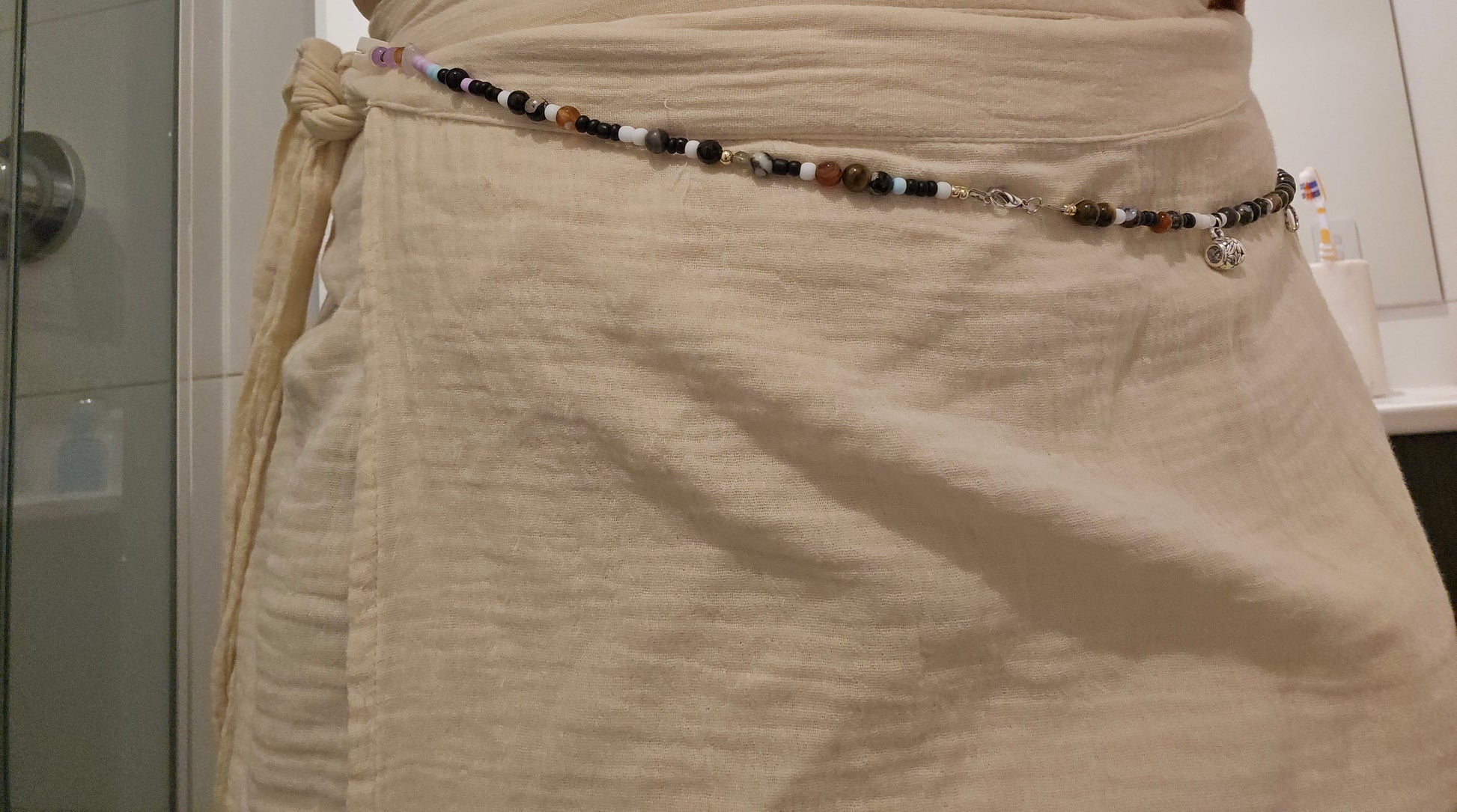 Beige skirt with a beaded belt in a bathroom setting