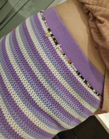 Purple and white striped garment with bead detailing on a mannequin.