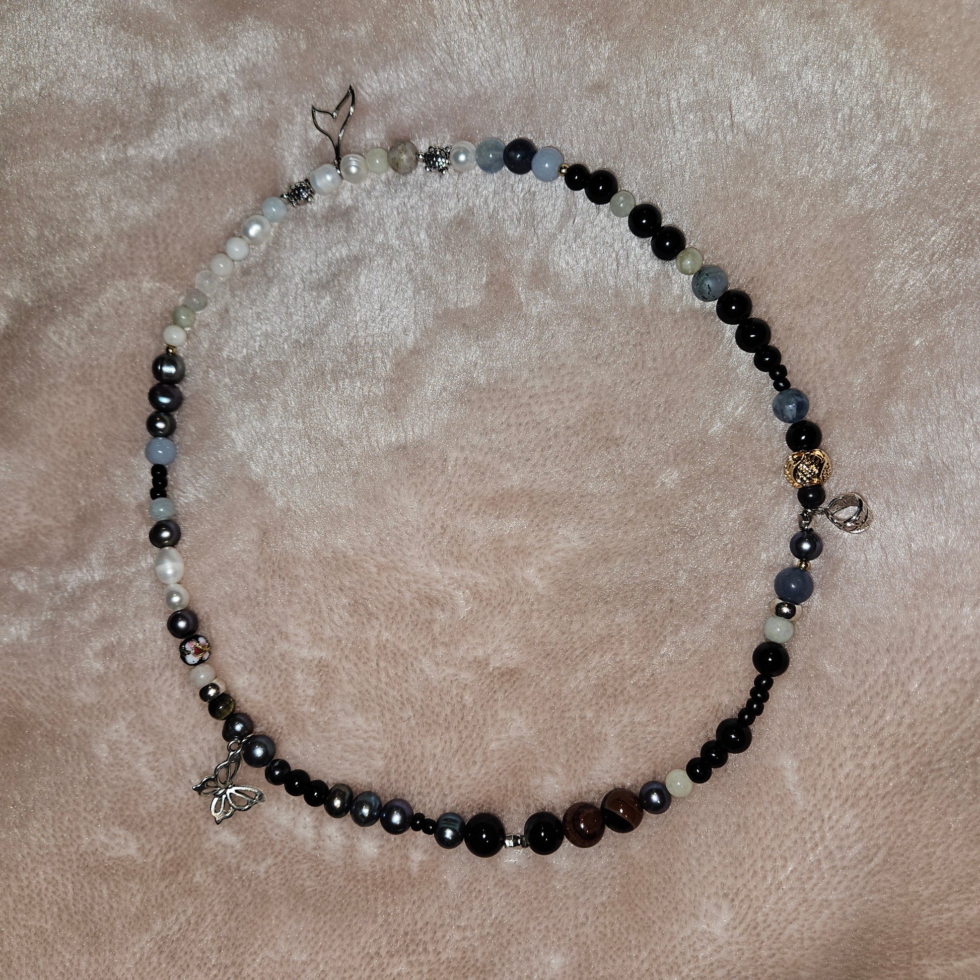 Necklace with black, white, and blue beads on a beige surface