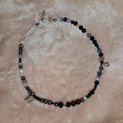 Necklace with black, white, and blue beads on a beige surface