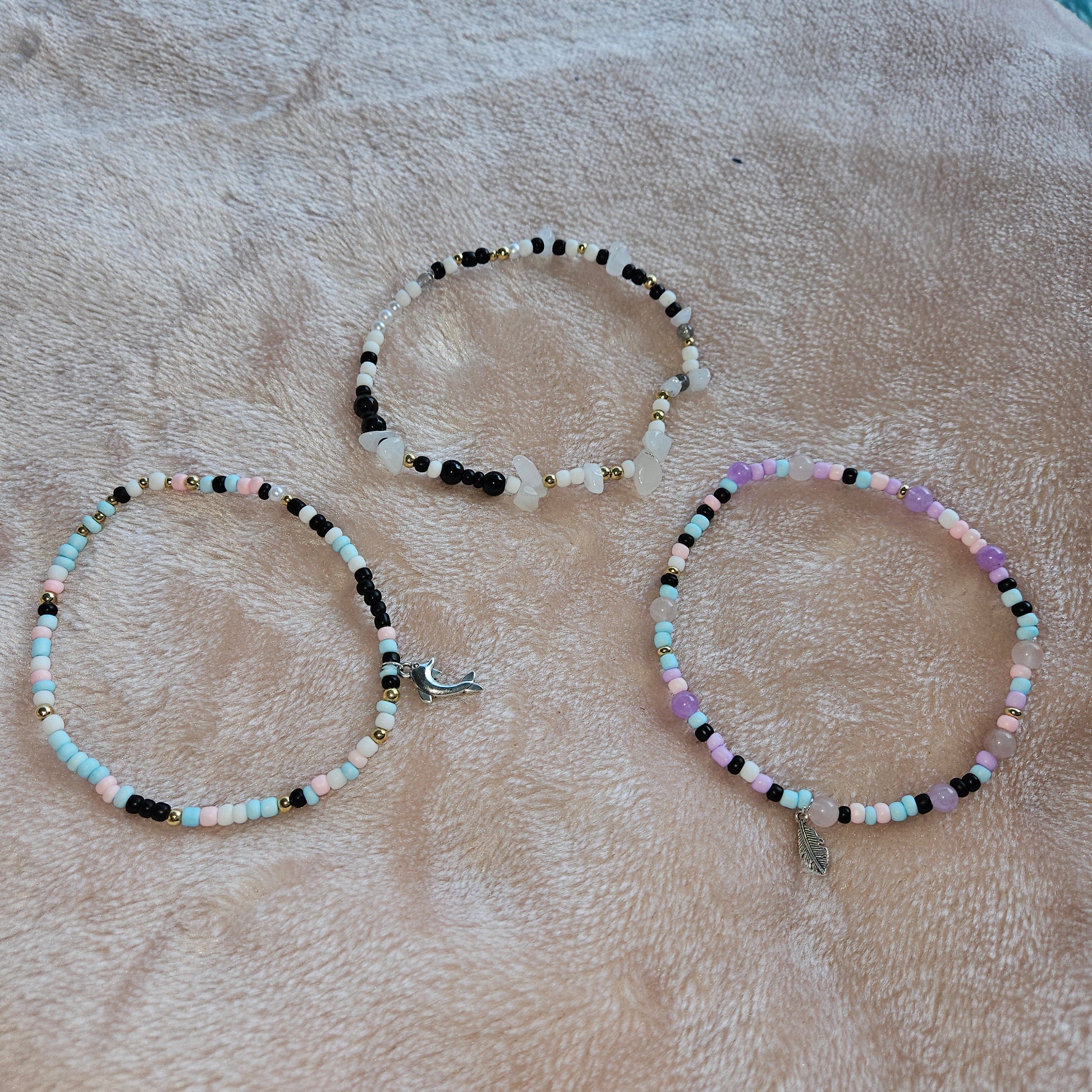 Three beaded necklaces on a textured beige surface